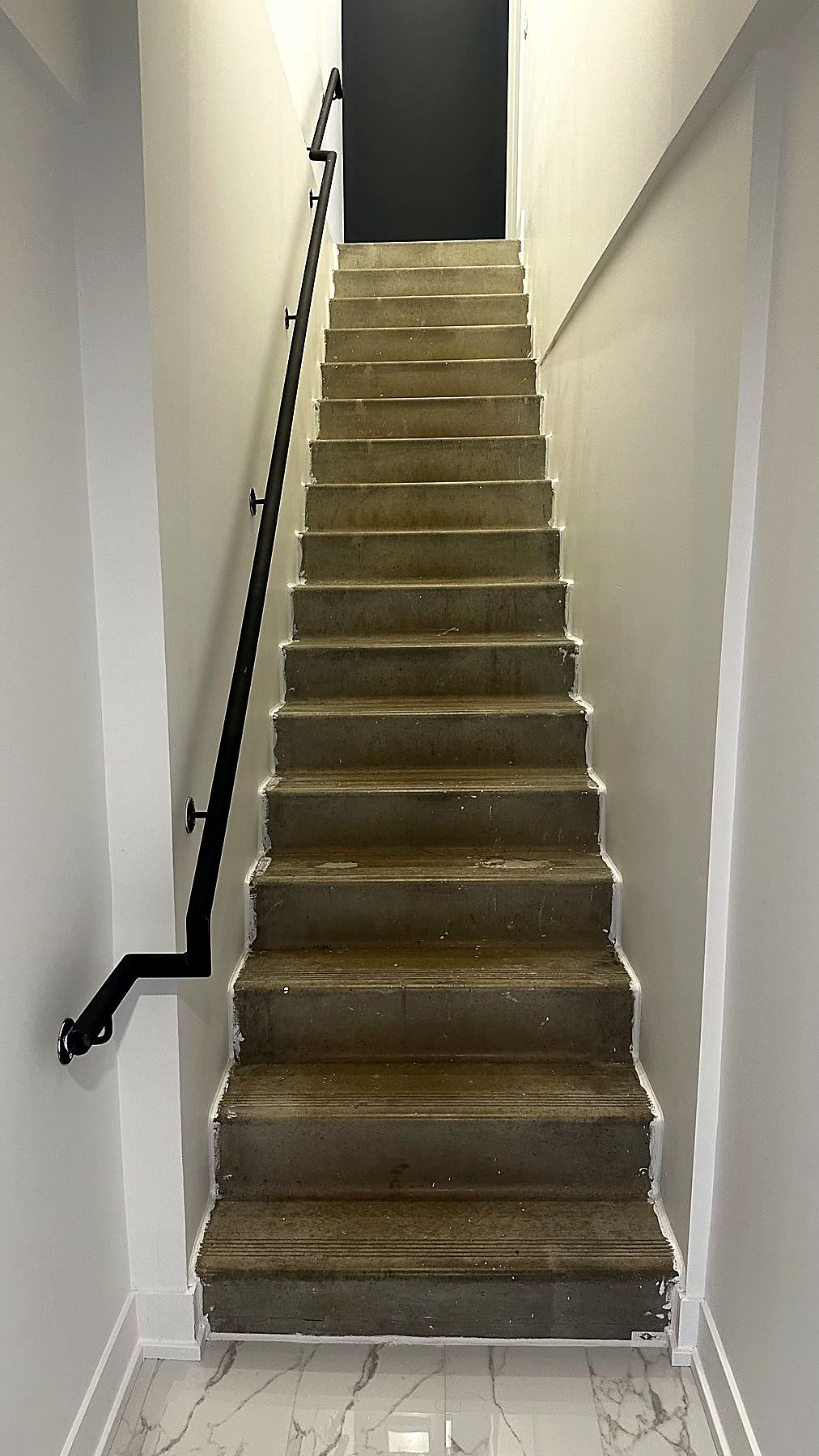 Tall stairwell with black steel staircase, wood treads and floor-to-ceiling windows
