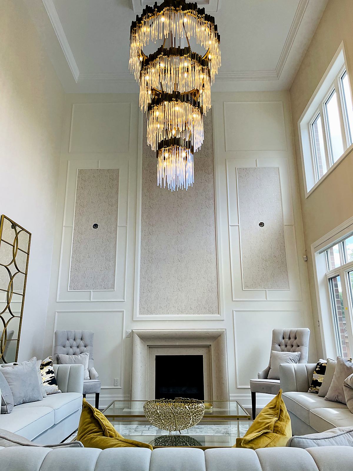 Two-storey great room with panelled walls, wallpaper inserts and a tiered chandelier
