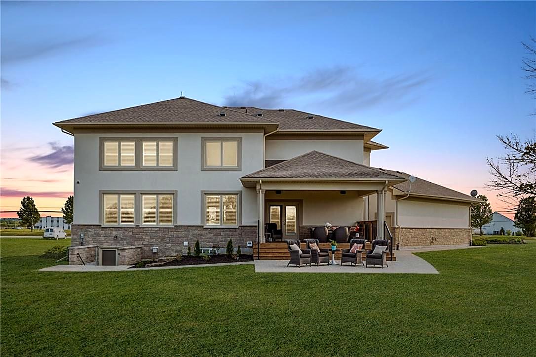 Rear exterior of a finished custom home at dusk with covered porch and patio seating
